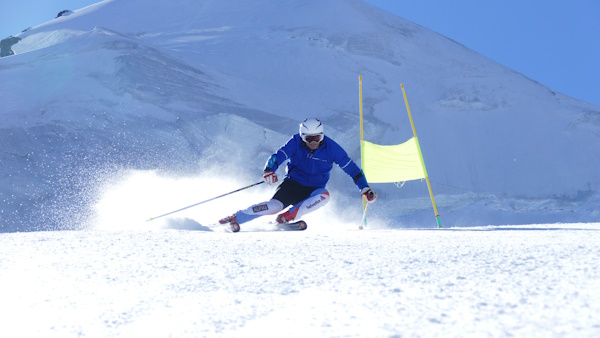 Skier in a racing stance on a groomed slope